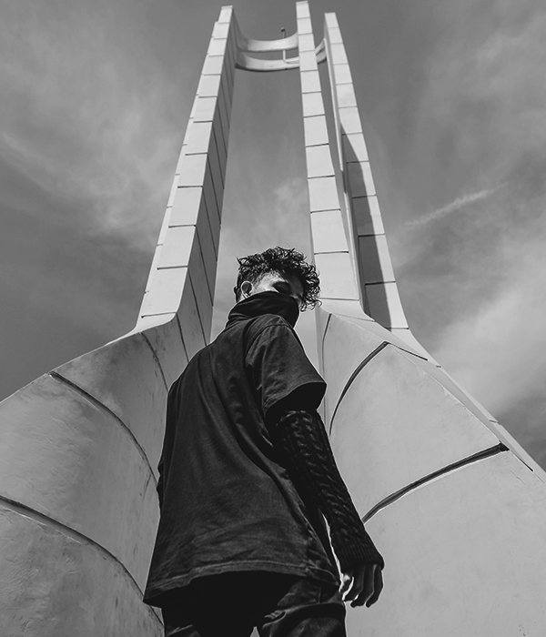 Person standing under a towering modern structure, viewed from below.